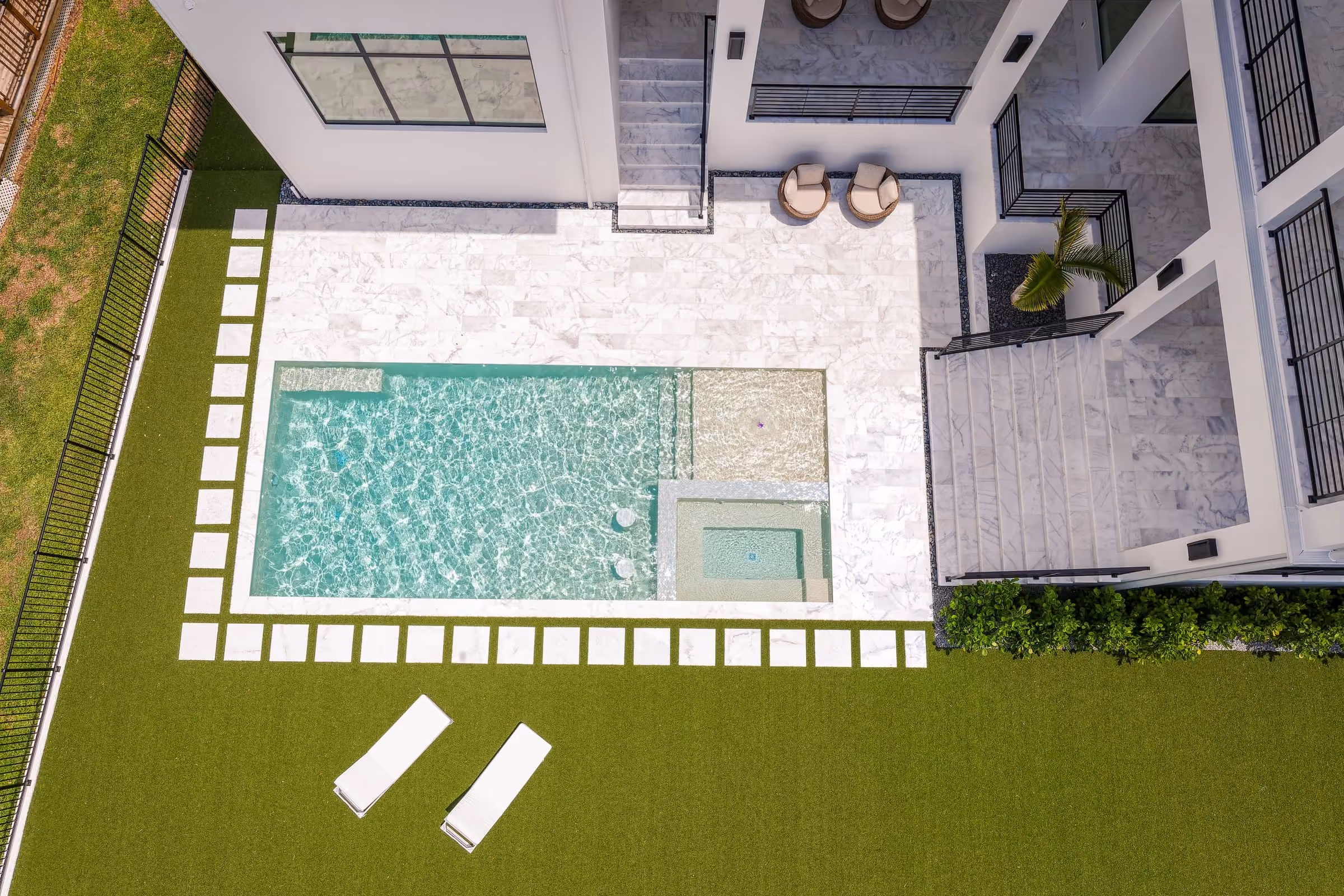 Aerial view of a pool courtyard with a turf lawn and lounge chairs