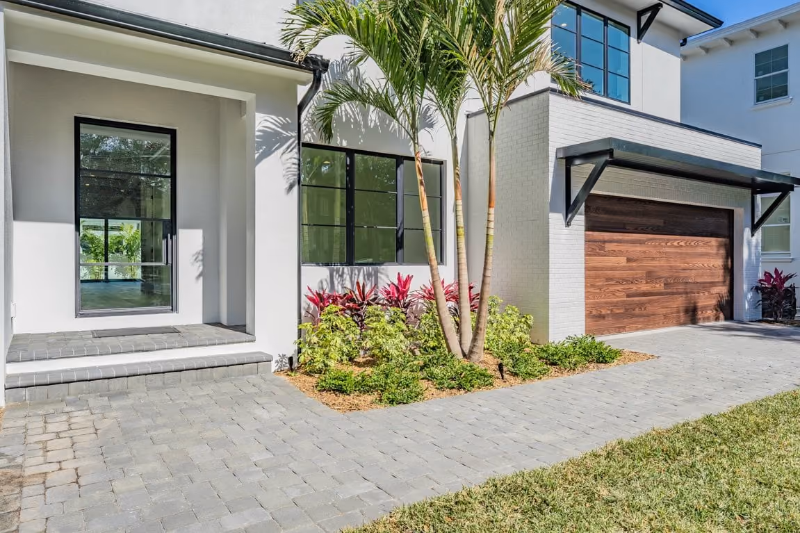 Entry with black-framed windows, a wood garage door and palms