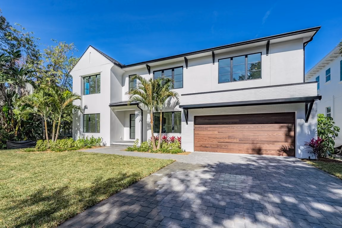 Two-story white home with a wood garage door and a paver drive