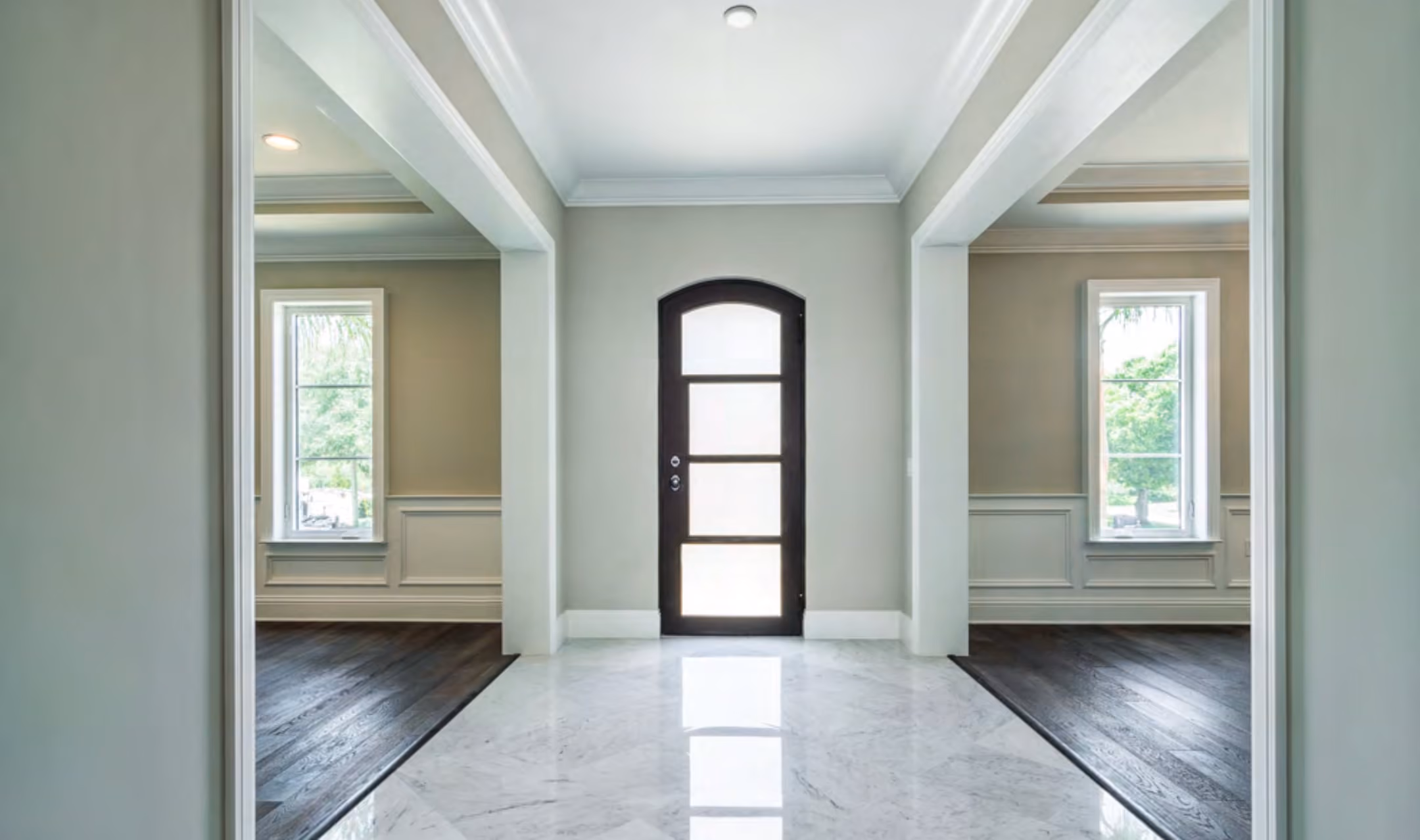 Foyer with an arched wood and glass front door and a marble floor