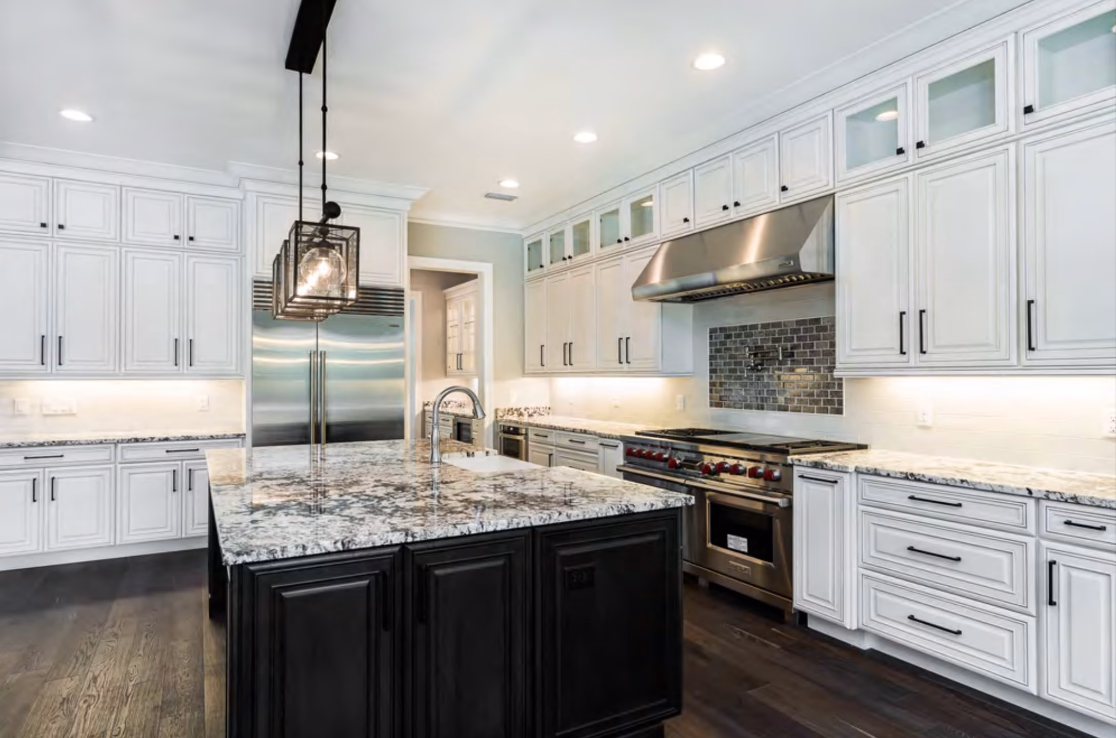 Kitchen with white cabinets, a dark island and granite counters