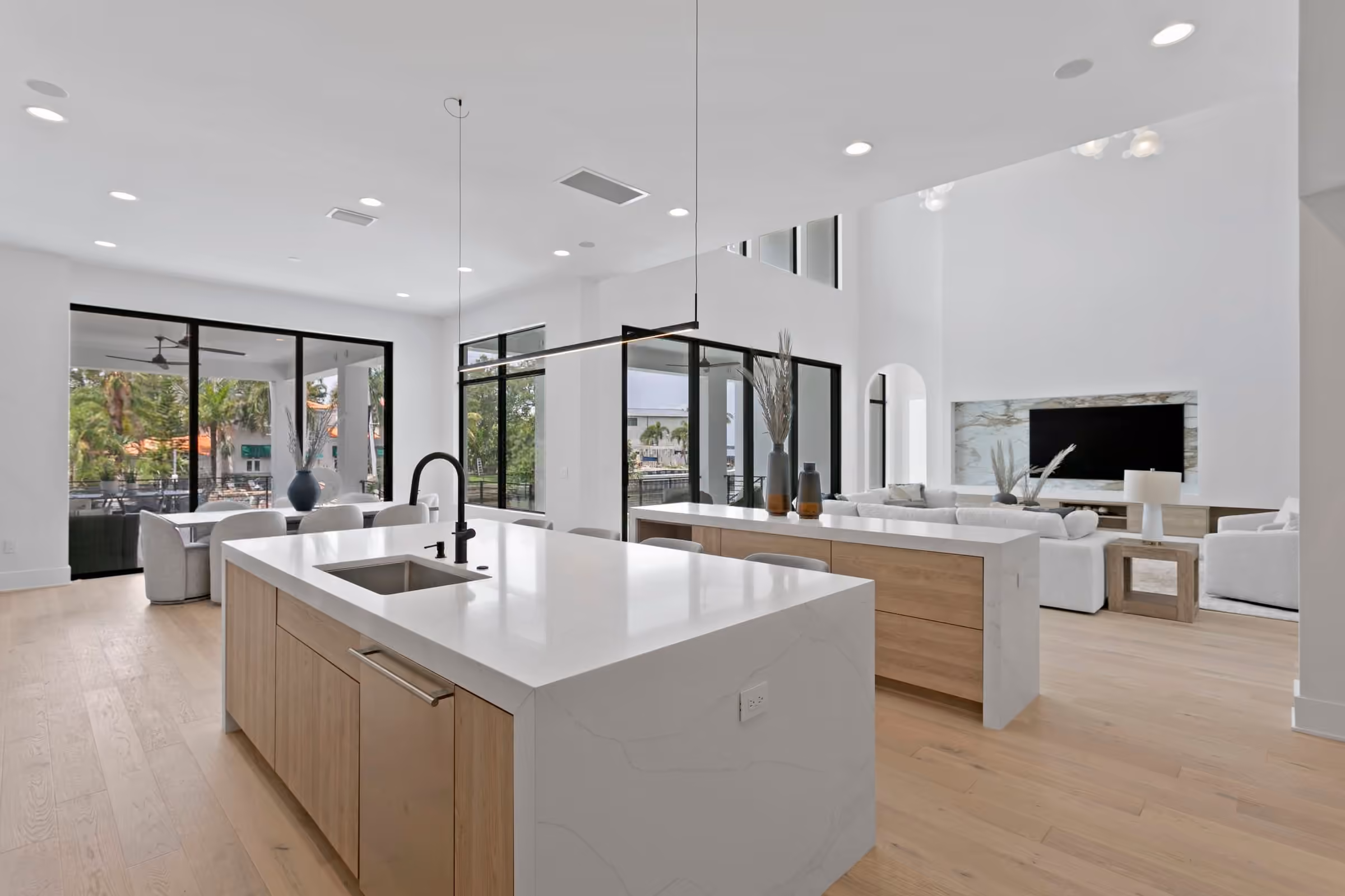Open kitchen and living area with a white island and black-framed glass walls