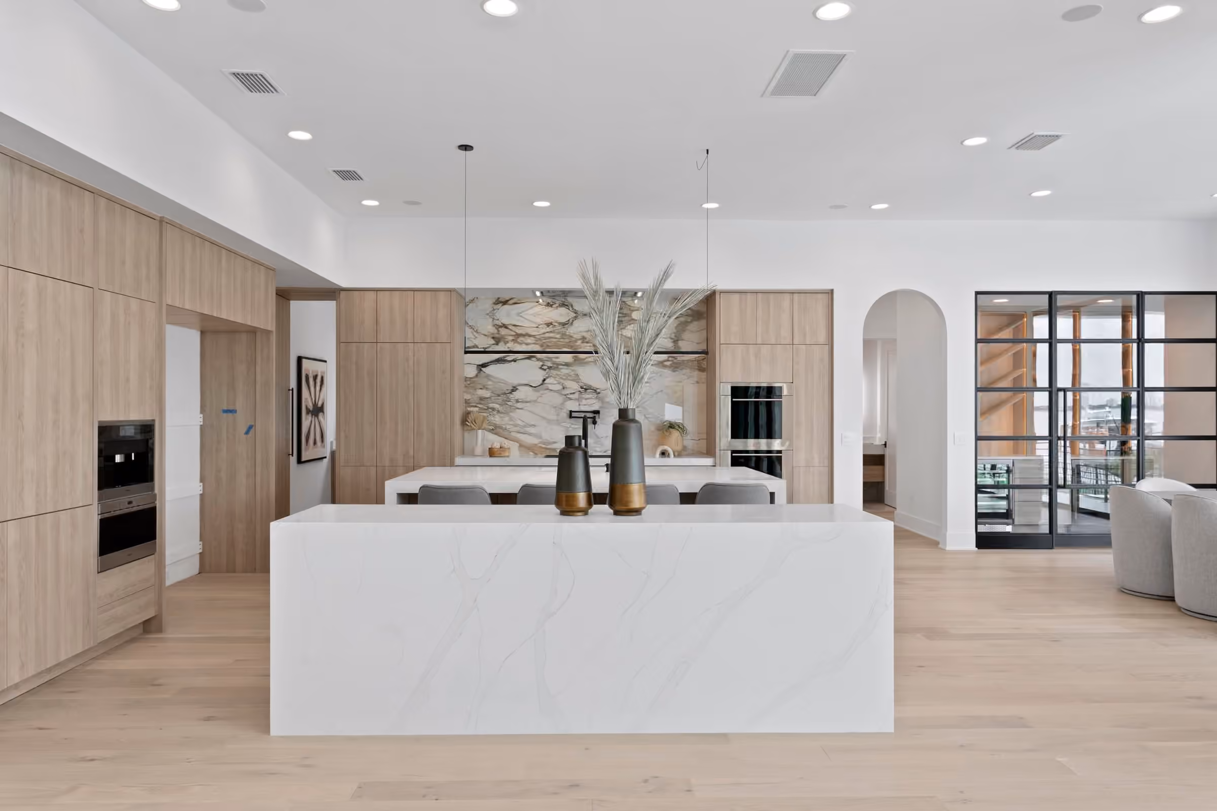 Kitchen with oak cabinets, a white waterfall island and an arched opening