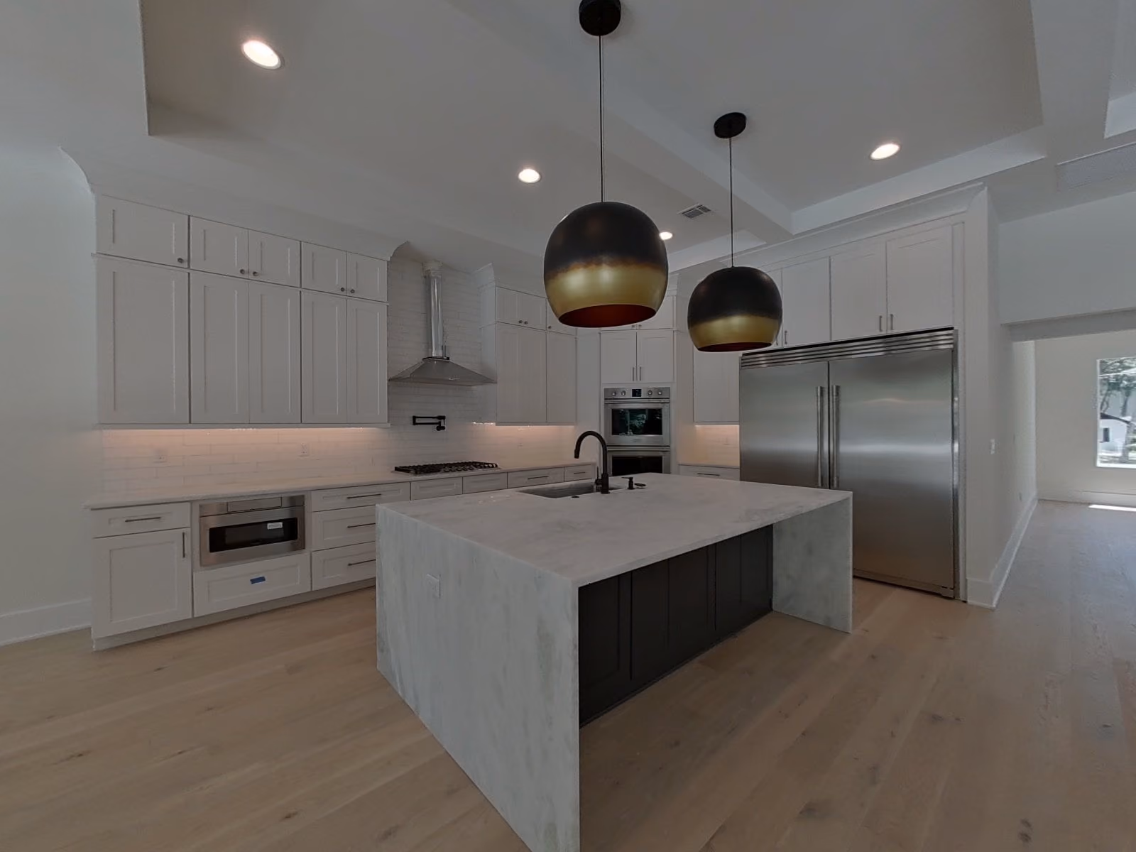Kitchen with a large island under black globe pendants