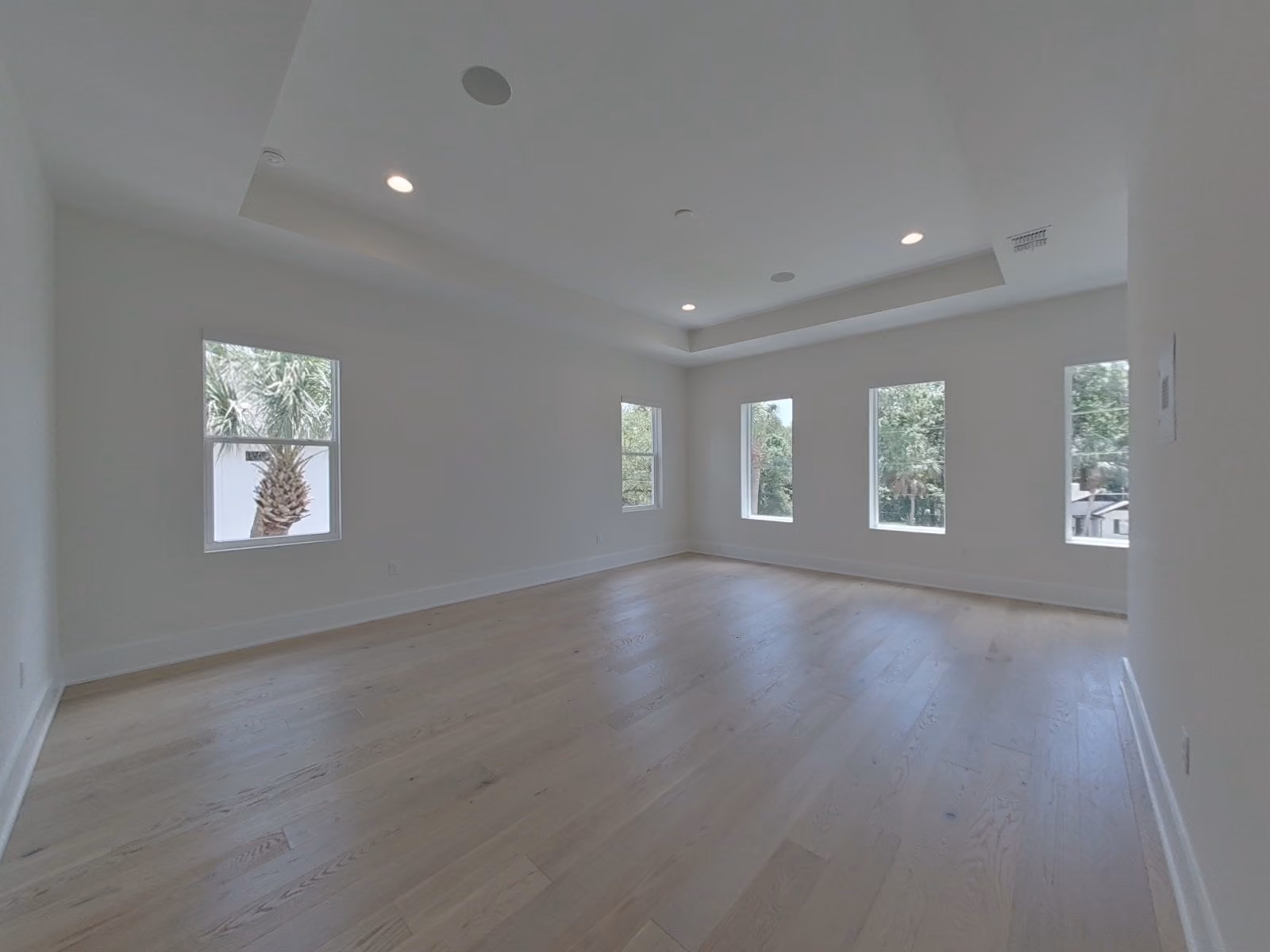 Living room with oak floors, a tray ceiling and windows on two sides