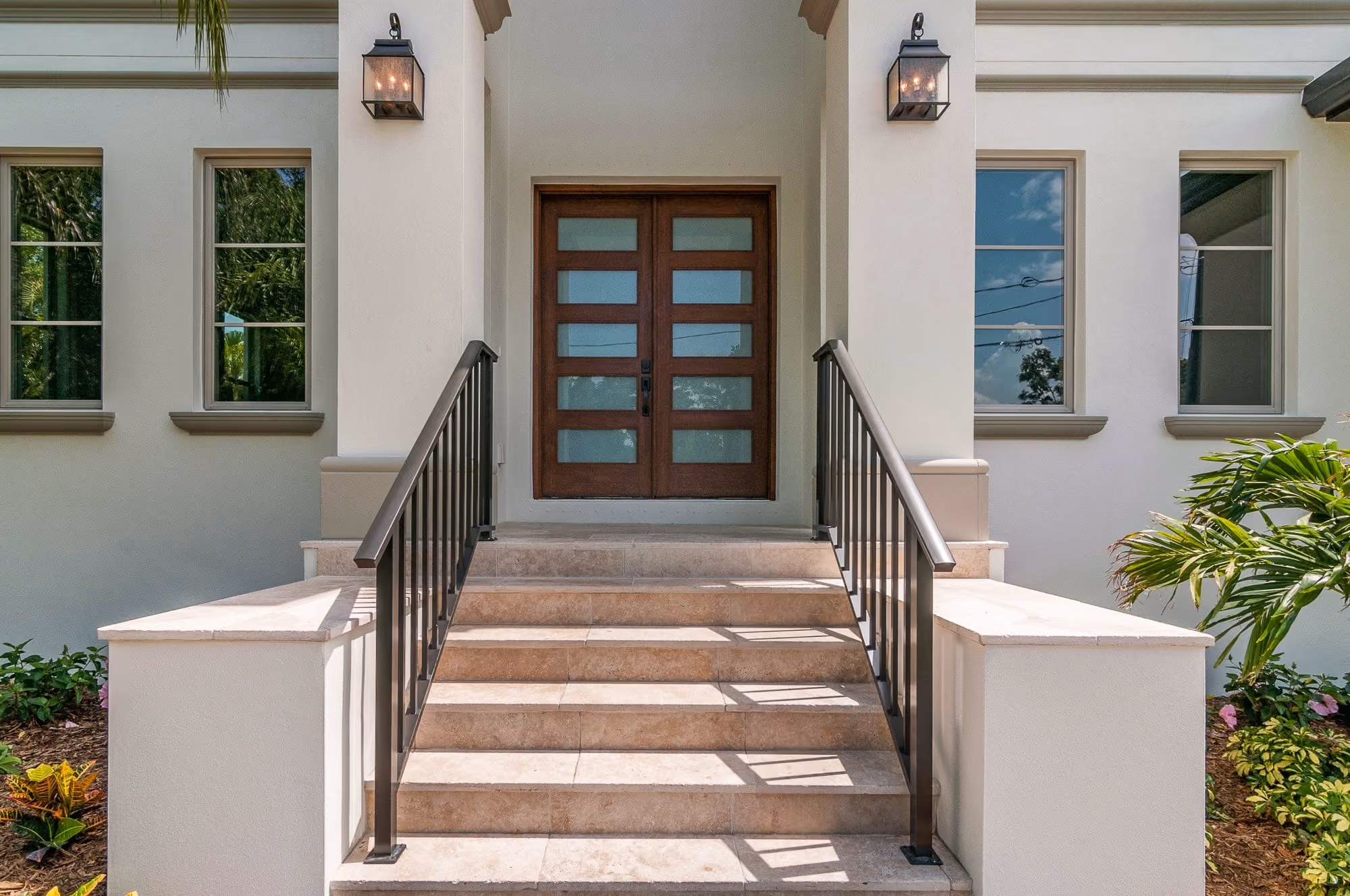 Entry steps up to a double wood door between two lanterns