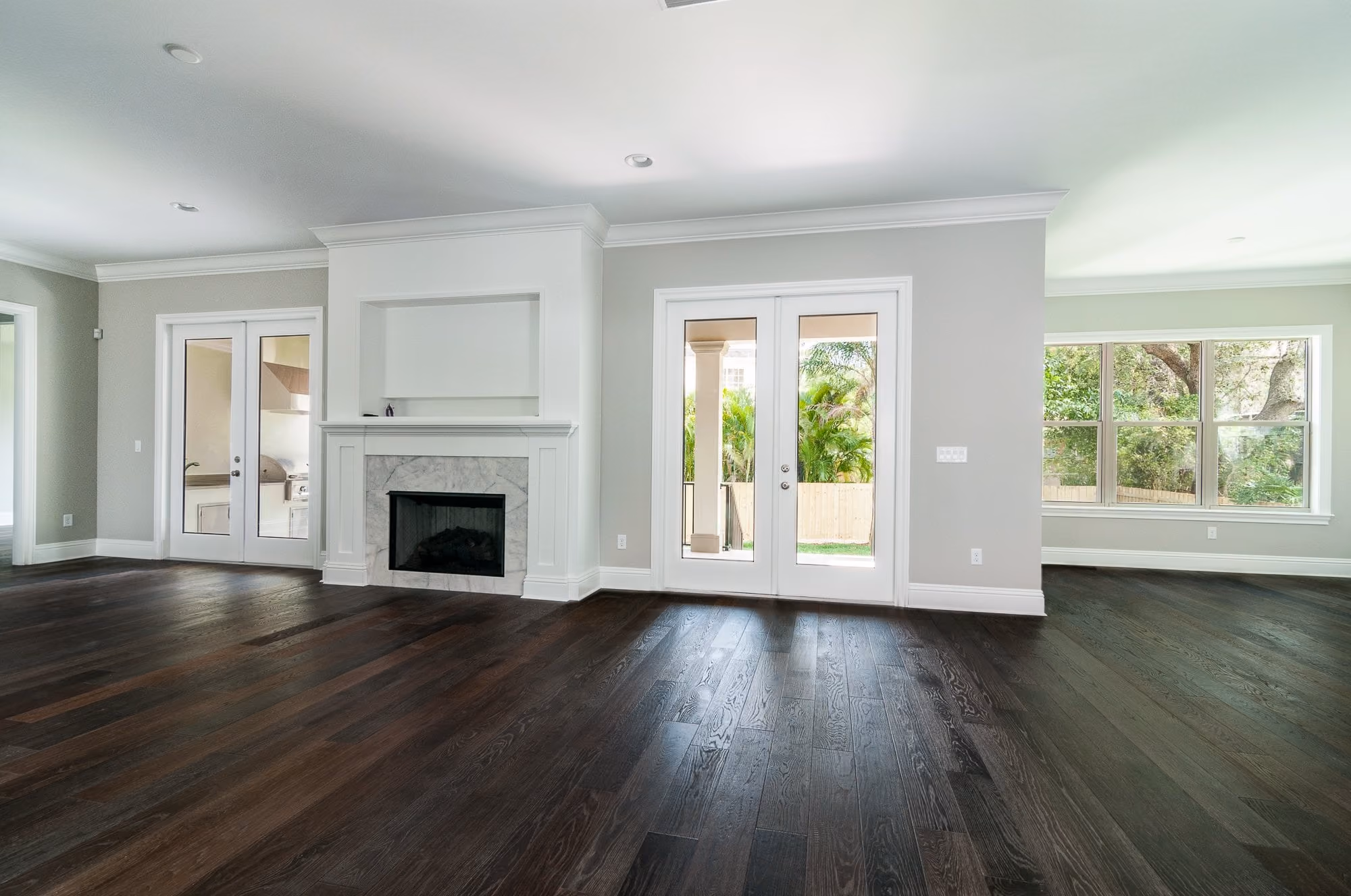 Family room with a fireplace and French doors over dark hardwood