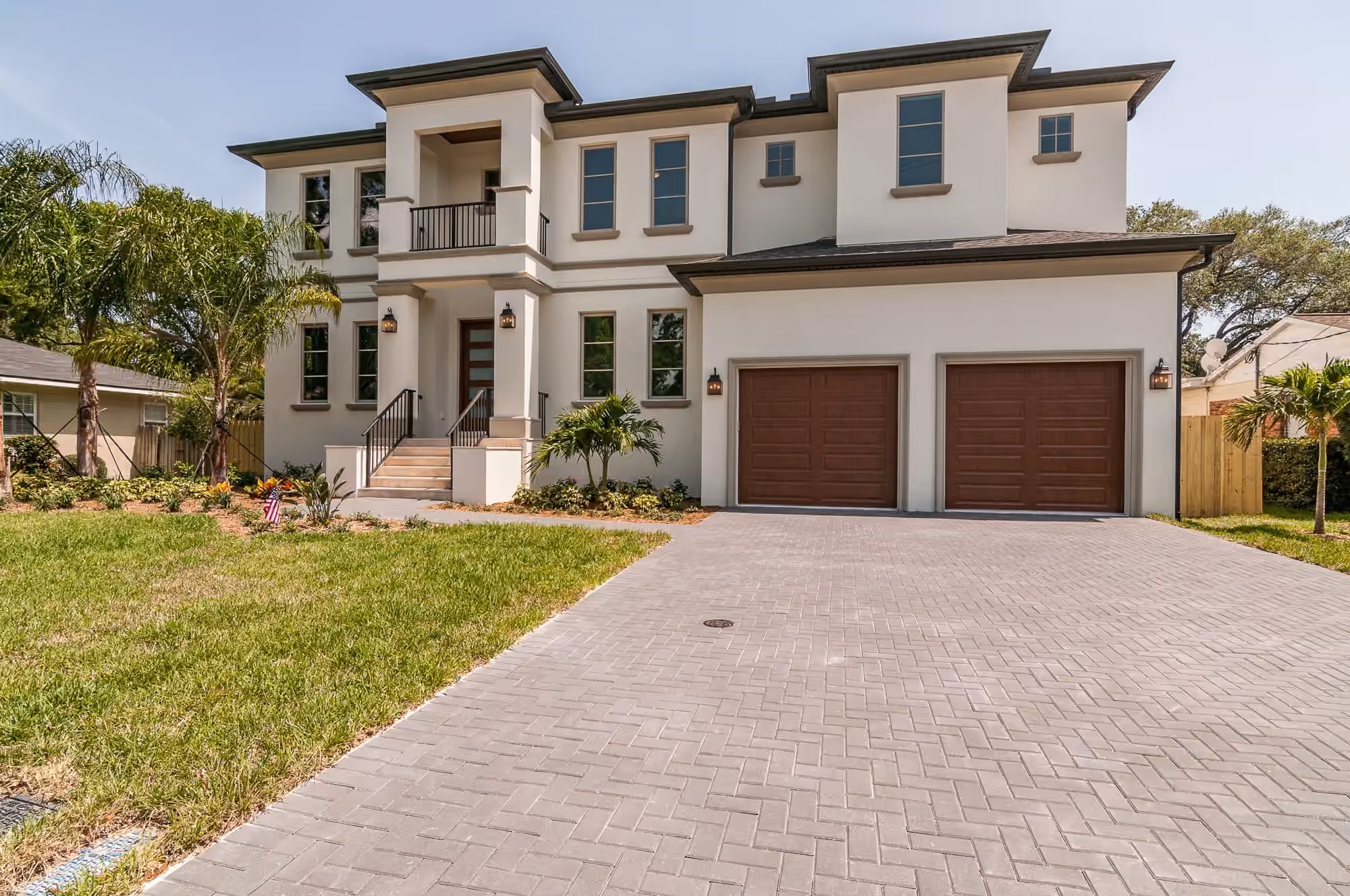 Two-story stucco home with two wood garage doors and a paver drive