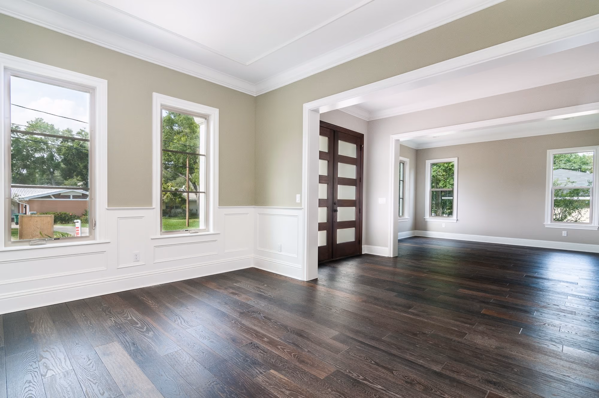 Living room with dark hardwood floors, wainscot and tall windows