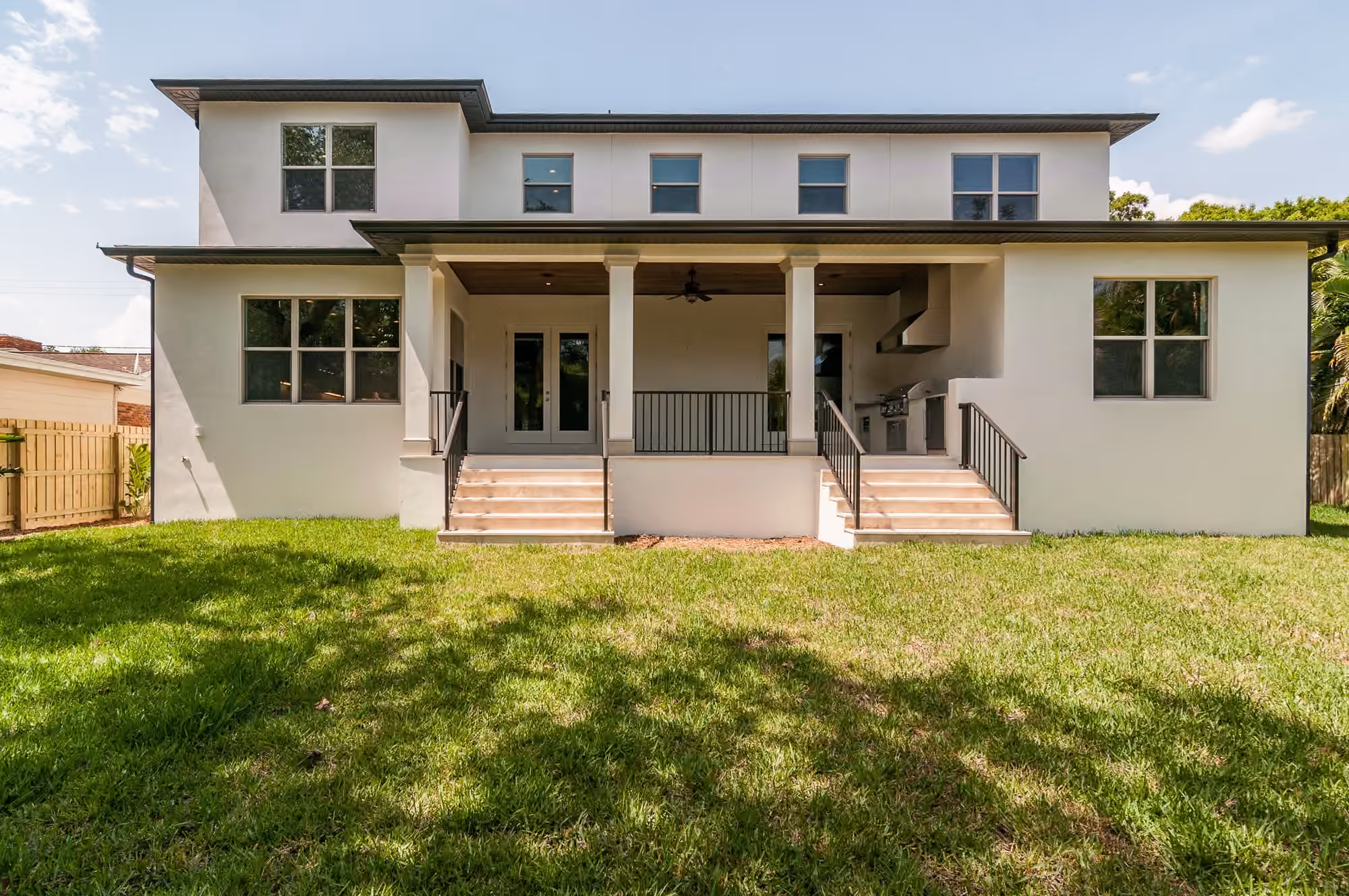 Rear of a two-story home with a covered porch and a lawn