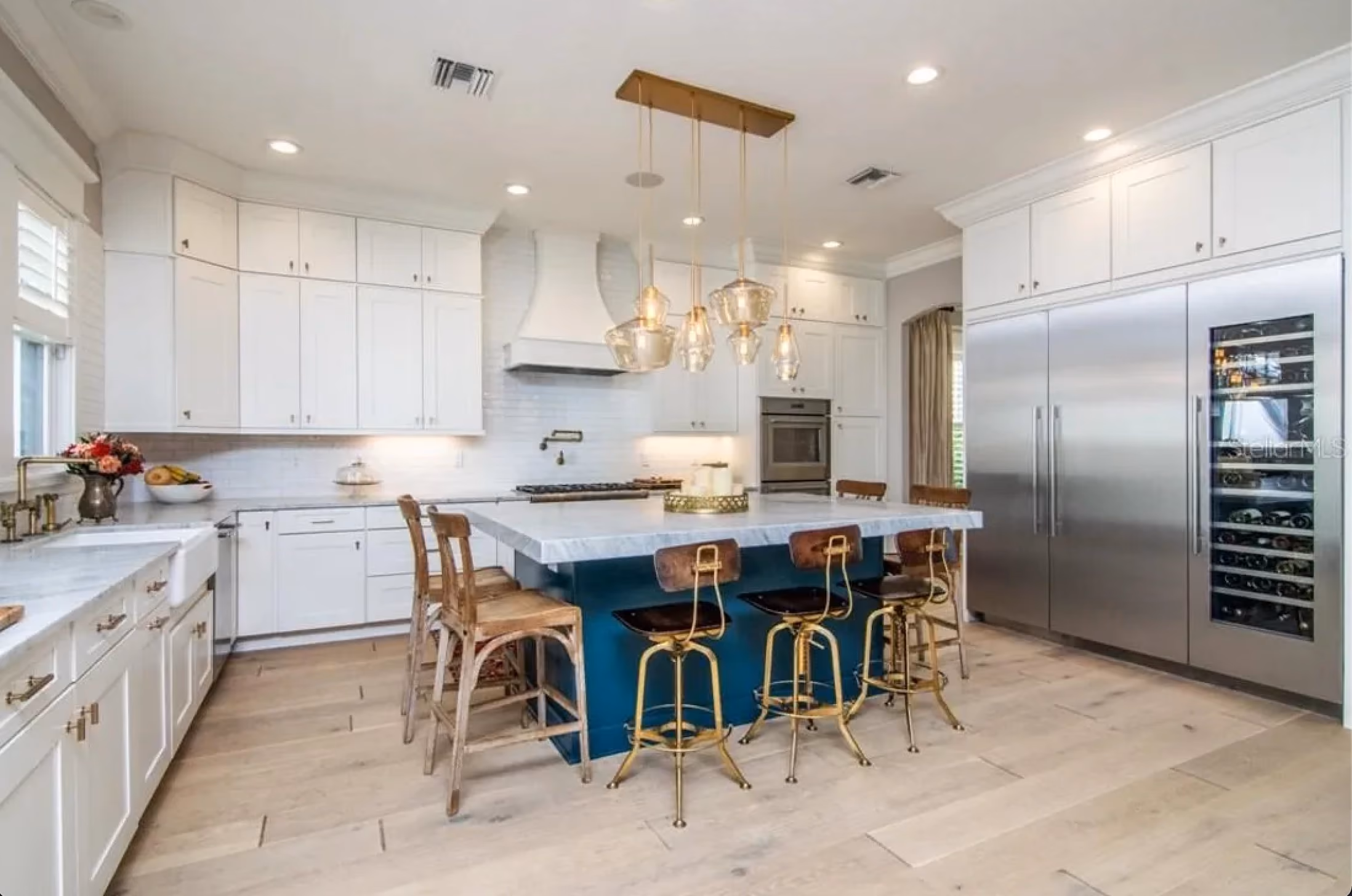Kitchen with a blue island, bar stools and stainless appliances