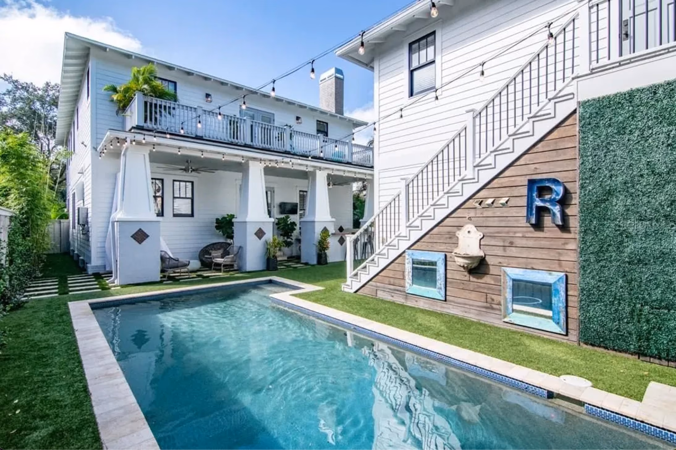 Backyard pool beside a two-story home with an exterior stair